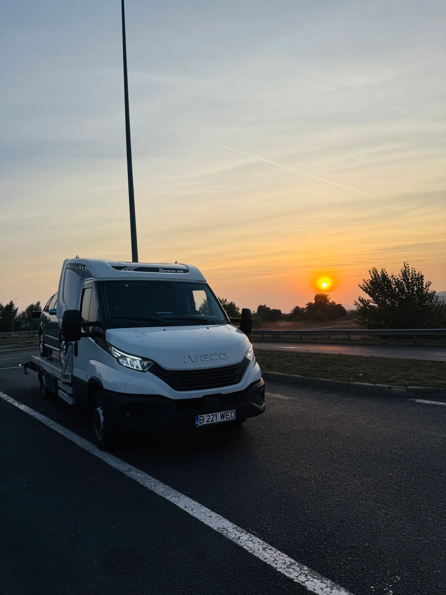 Autoplatforma Diava Cars pe o parcare de autostradă, la apus, înainte de o cursă internațională